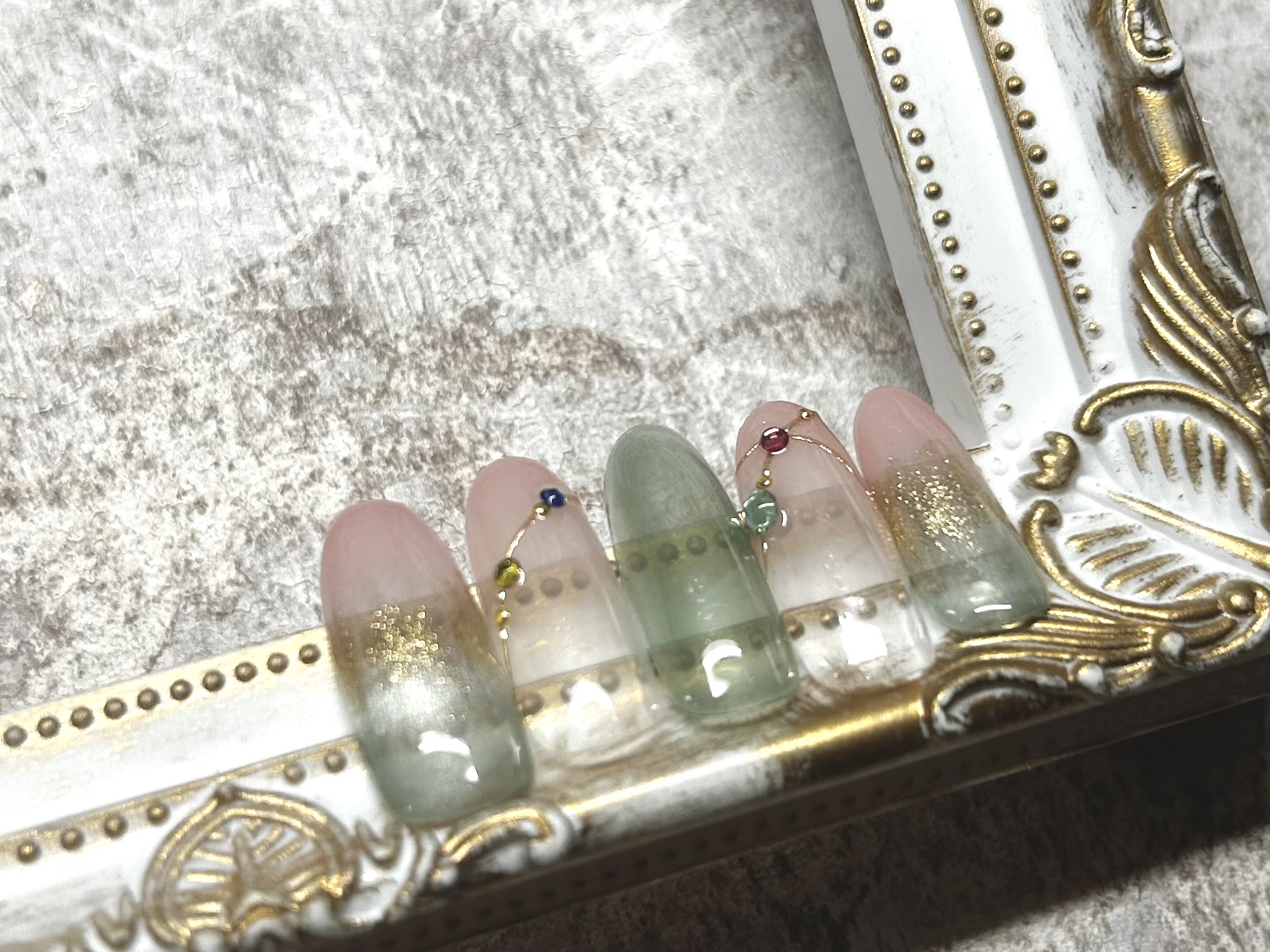 Delicate Japanese gel nail design with translucent colours and gold lines at a Ginza nail salon